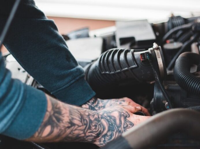 person in blue denim jeans and black and white adidas sneakers riding on black motorcycle