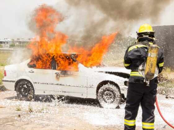 firefighter fighting burning car