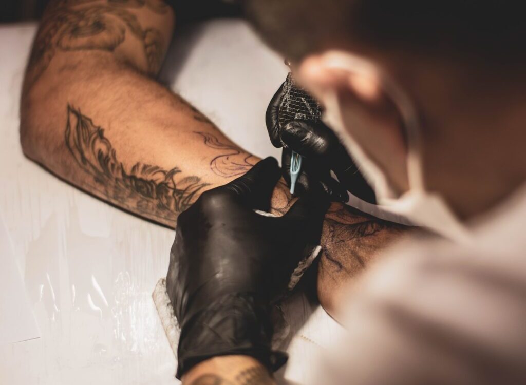 shallow focus photo of person tattooing person's right arm