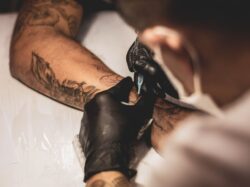 shallow focus photo of person tattooing person's right arm