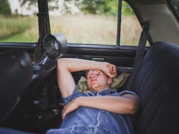 person in blue denim shirt sleeping behind the car seat