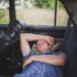 person in blue denim shirt sleeping behind the car seat