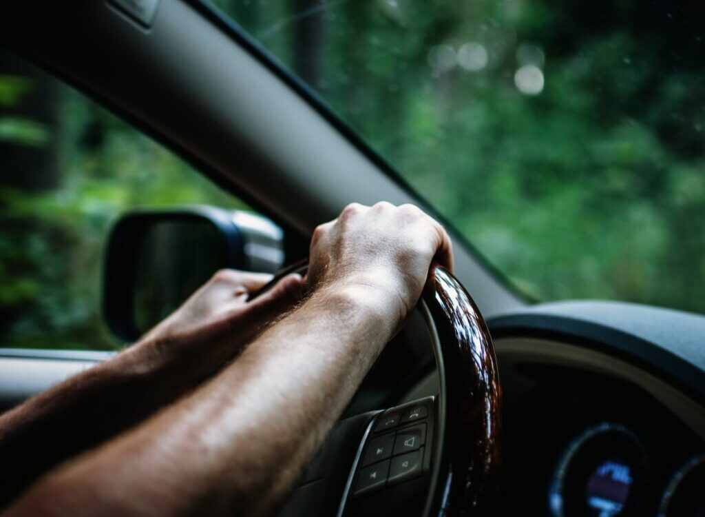 person holding car steering wheel
