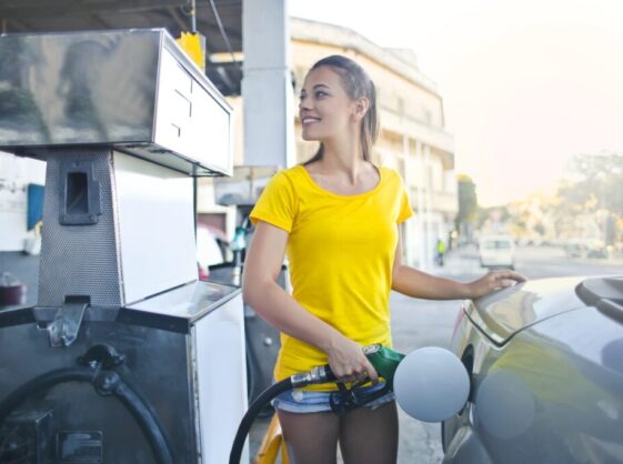 Woman in Yellow Shirt While Filling Up Her Car With Gasoline