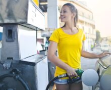 Woman in Yellow Shirt While Filling Up Her Car With Gasoline