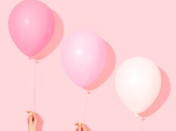 person holding pink and white balloon