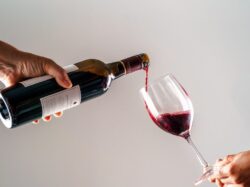 a person pouring a glass of wine into another person's hand