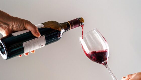 a person pouring a glass of wine into another person's hand