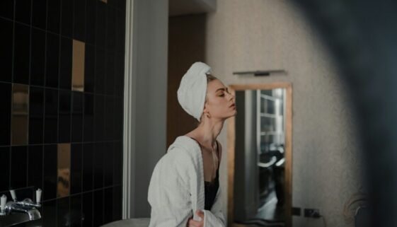 woman in white robe standing in front of mirror
