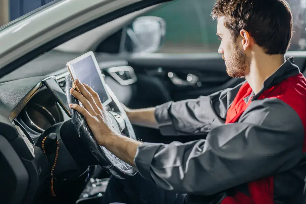 Automechanik sedící v autě, provádějící diagnostiku.