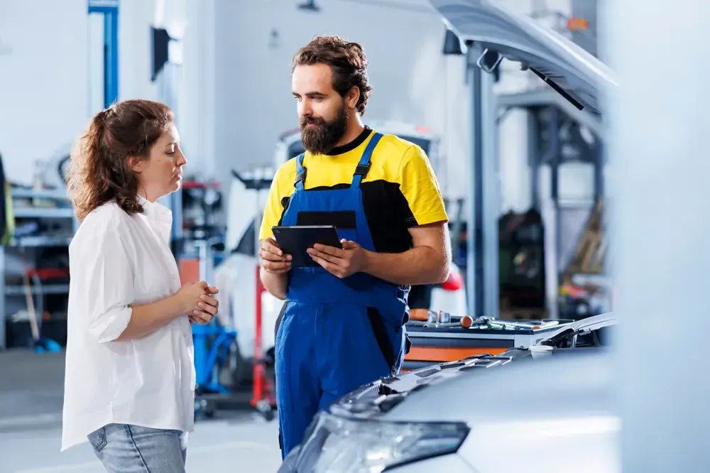 Žena hovořící s automechanikem v servisu.