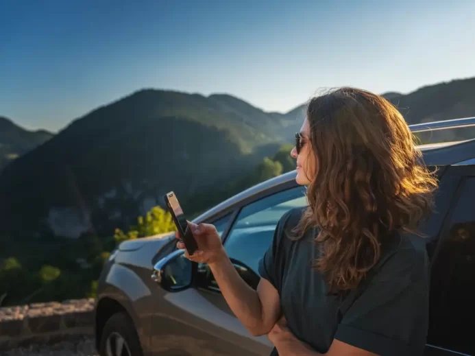 žena opřená o auto se dívá na krajinu