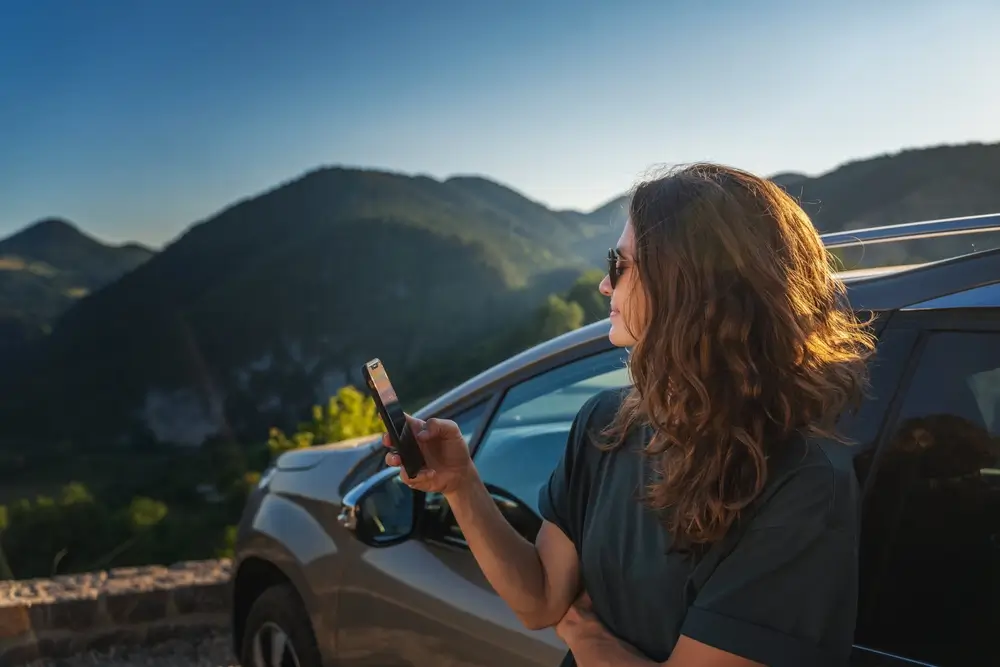 žena opřená o auto se dívá na krajinu