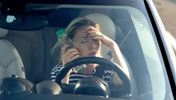 Unavená žena sedící za volantem.