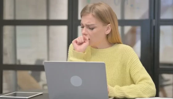 Kašlající žena u notebooku