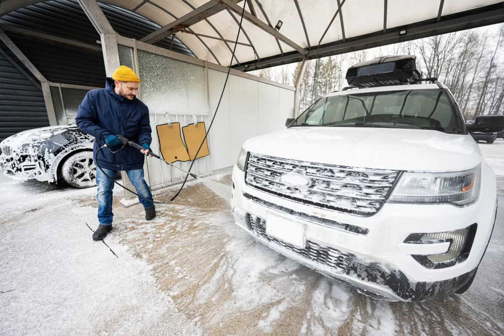 Muž myjící auto v ruční myčce.