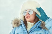 žena v zimě nosí sluneční brýle na horách a chrání své oči