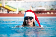 žena se koupe v bazéně a na hlavě má vánoční čepici