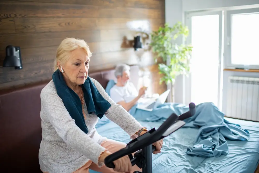 seniorka jede na rotopedu a manžel odpočívá