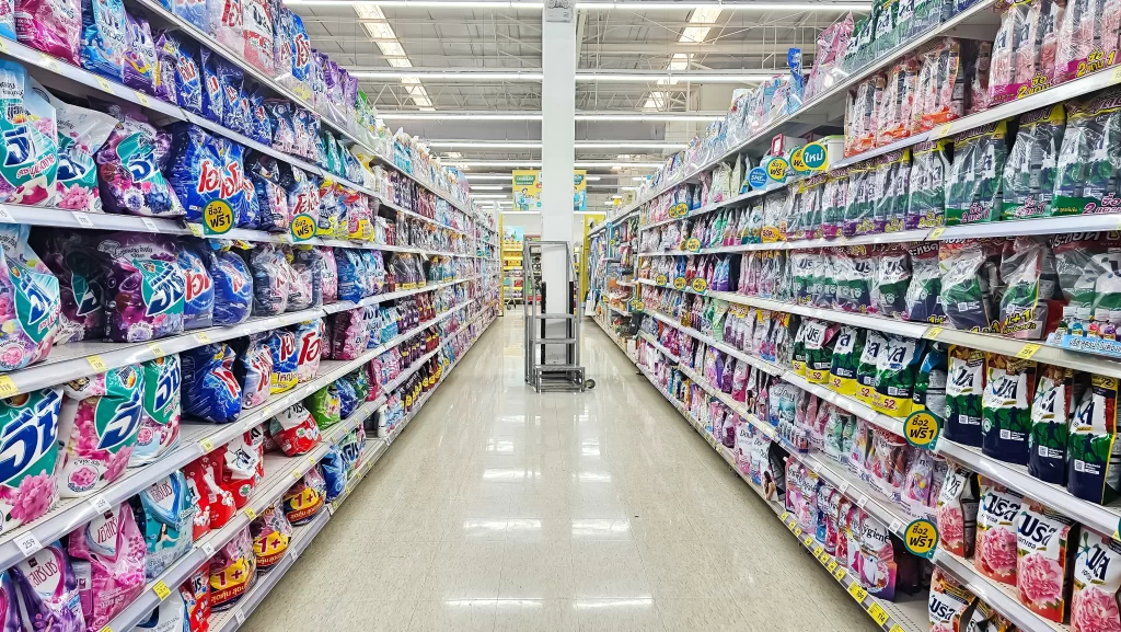 Dlouhé regály v supermarketu pod umělým osvětlením.