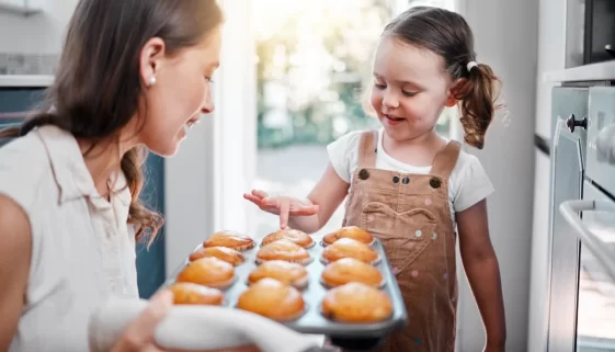 žena s dítětem drží plech plný muffinů