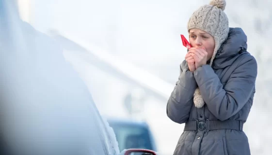 žena čistí sklo auta v zimě