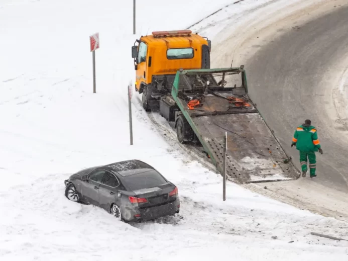 Asistenční služba vytahující auto sjeté ze zimní vozovky.