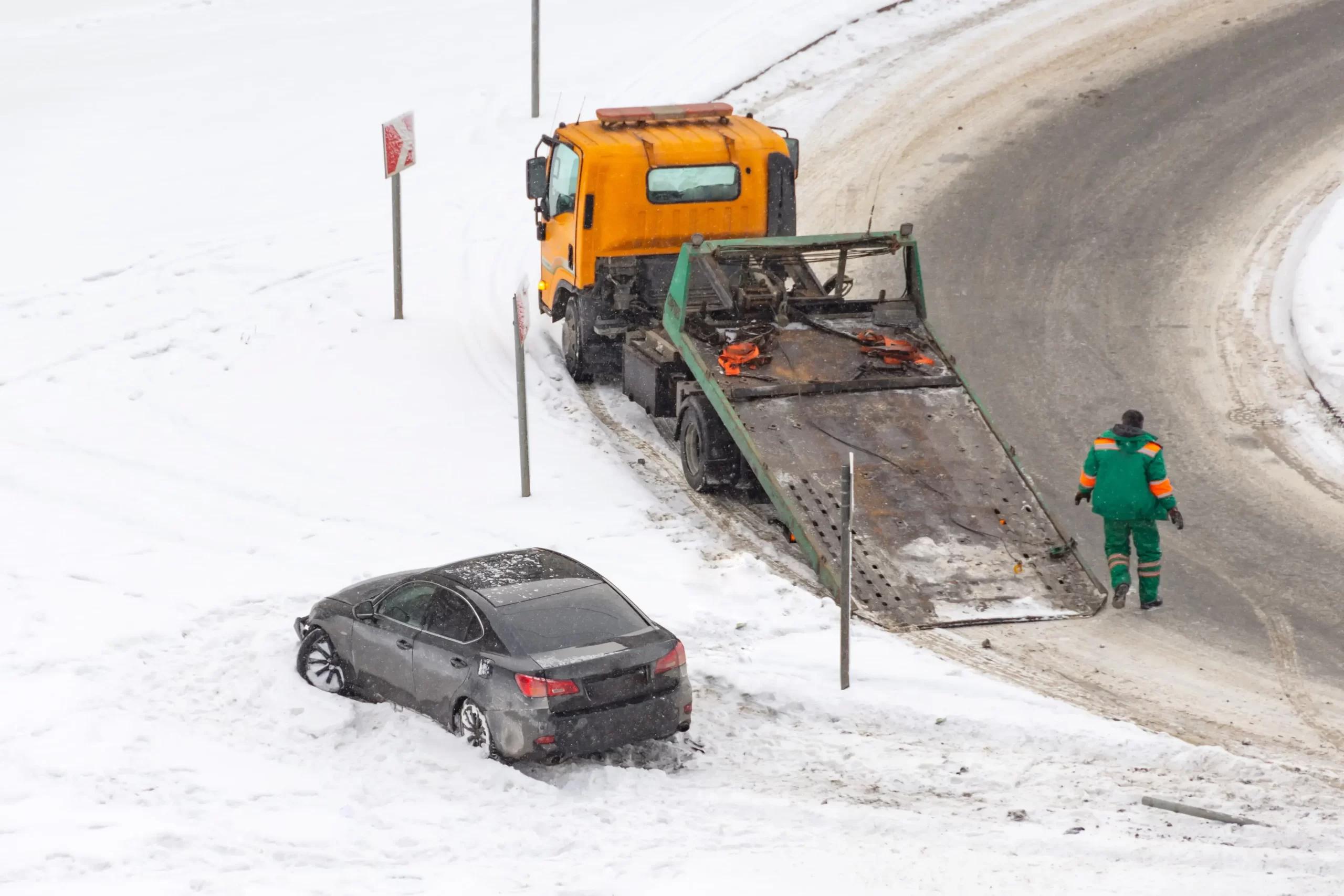 Asistenční služba vytahující auto sjeté ze zimní vozovky.