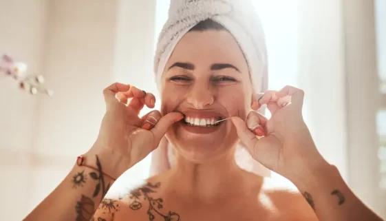 Žena v turbanu používající zubní nit.