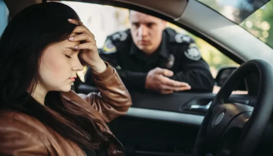 Nešťastná žena za volantem s policistou u vozu.