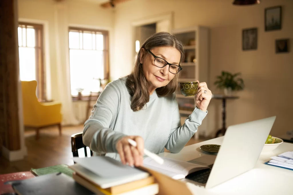 shutterstock_1807250869 - MotorGuru.cz Starší žena sedí za počítačem a počítá si důchod.