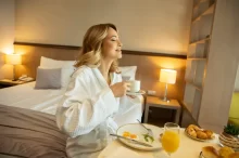žena v hotelovém pokoji snídá vajíčka, volská oka a chutná jí