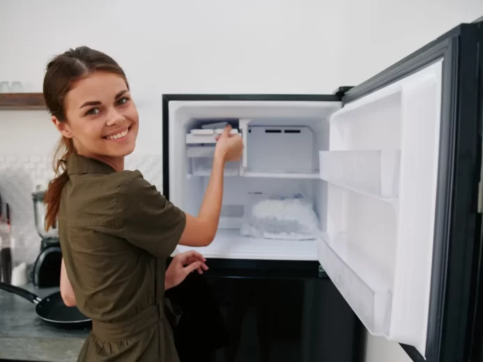 žena vkládá jídlo do lednice a usmívá se do objektivu