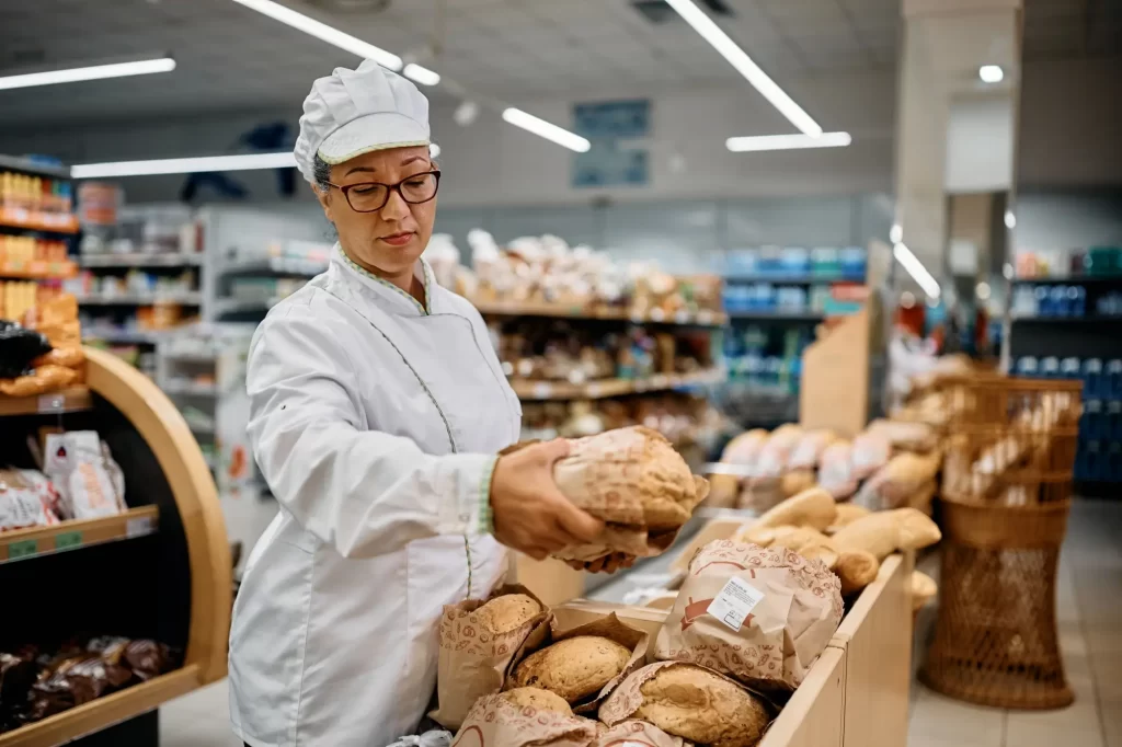 Pekařka v supermarketu skládá chléb