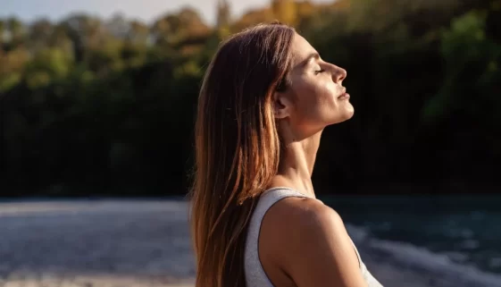 žena nasává teplo slunce a je šťastná, protože je zdravá
