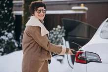 Žena nabíjející elektromobil v zimě.