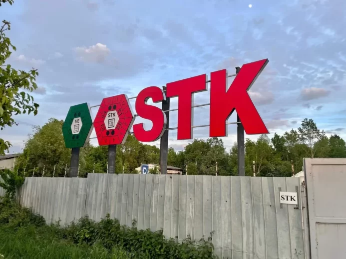 Značka Stanice technické kontroly tyčící se nad dřevěným plotem