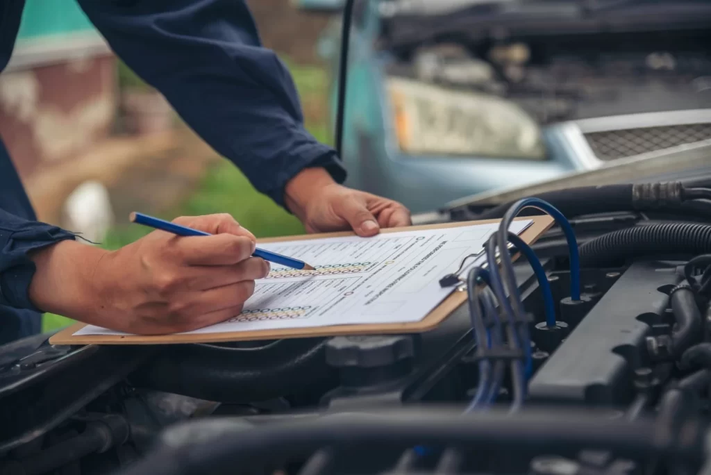 Několik dní bez technické kontroly znamená pokutu - MotorGuru.cz Automobilový mechanik si na motoru auta odškrtává položky