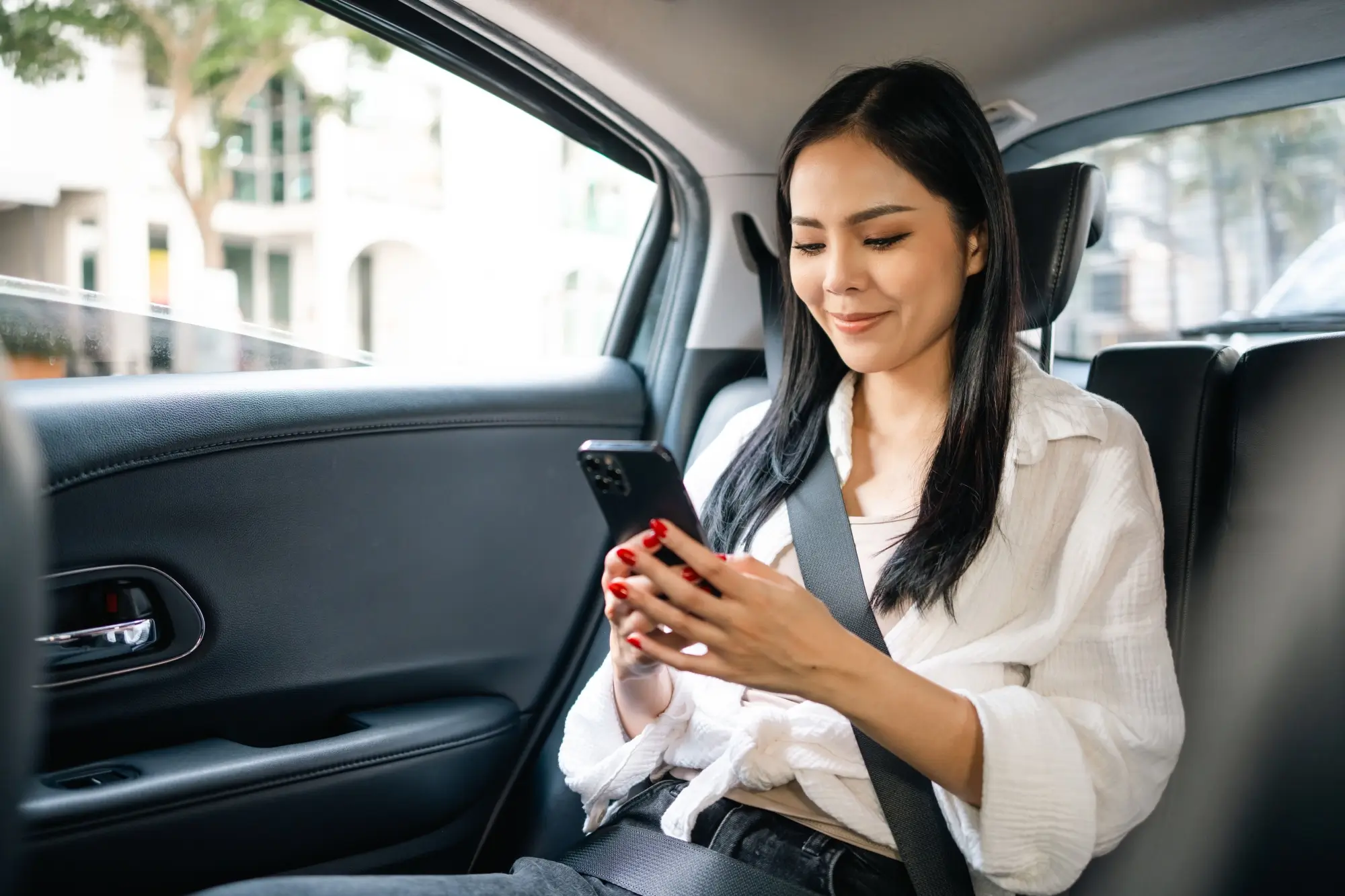 - MotorGuru.cz Hezká žena v autě pracující s aplikací v telefonu.