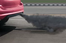 Pohled na zadní část osobního automobilu vypouštějící tmavý kouř z výfuku