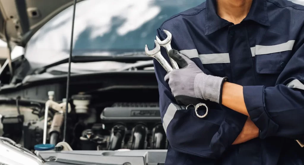 Automechanik s nářadím v ruce.
