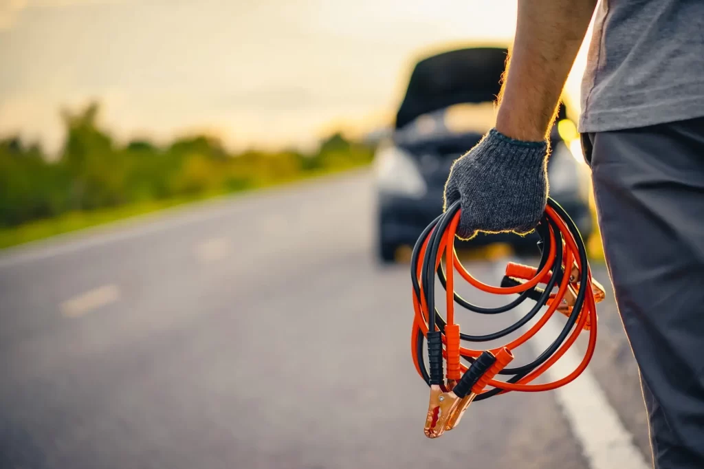 Shutterstock_auto3 - MotorGuru.cz Muž s nabíjecími kabely, auto v pozadí