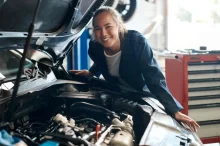 Žena stojí vedle motoru auta