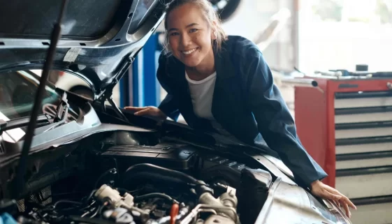 Žena stojí vedle motoru auta