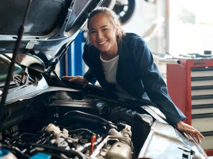 Žena stojí vedle motoru auta
