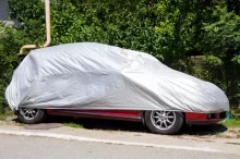 Auto stojí na kraji silnice pod ochrannou plachtou