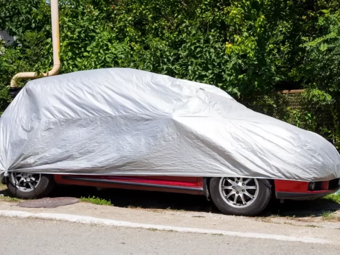 Auto stojí na kraji silnice pod ochrannou plachtou