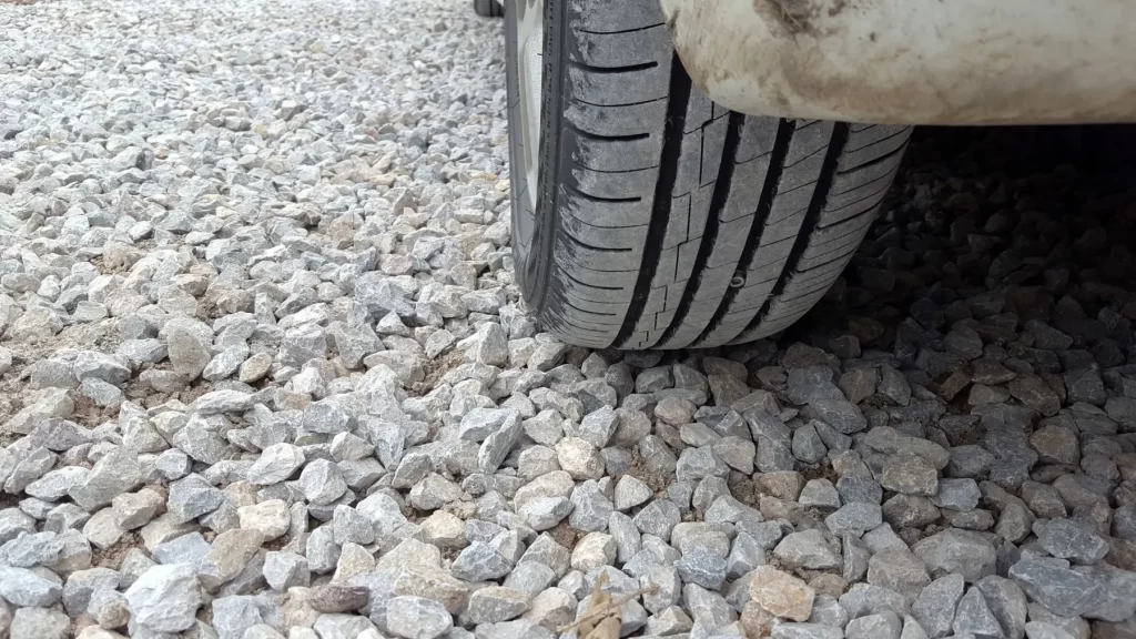 - MotorGuru.cz Detailní záběr automobilové pneumatiky stojící na štěrku