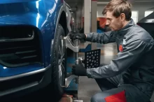 Muž kontroluje seřízení kol v autoservisu