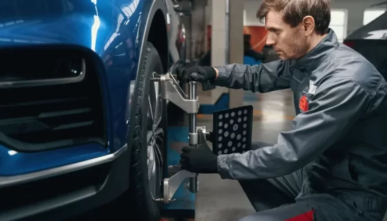 Muž kontroluje seřízení kol v autoservisu